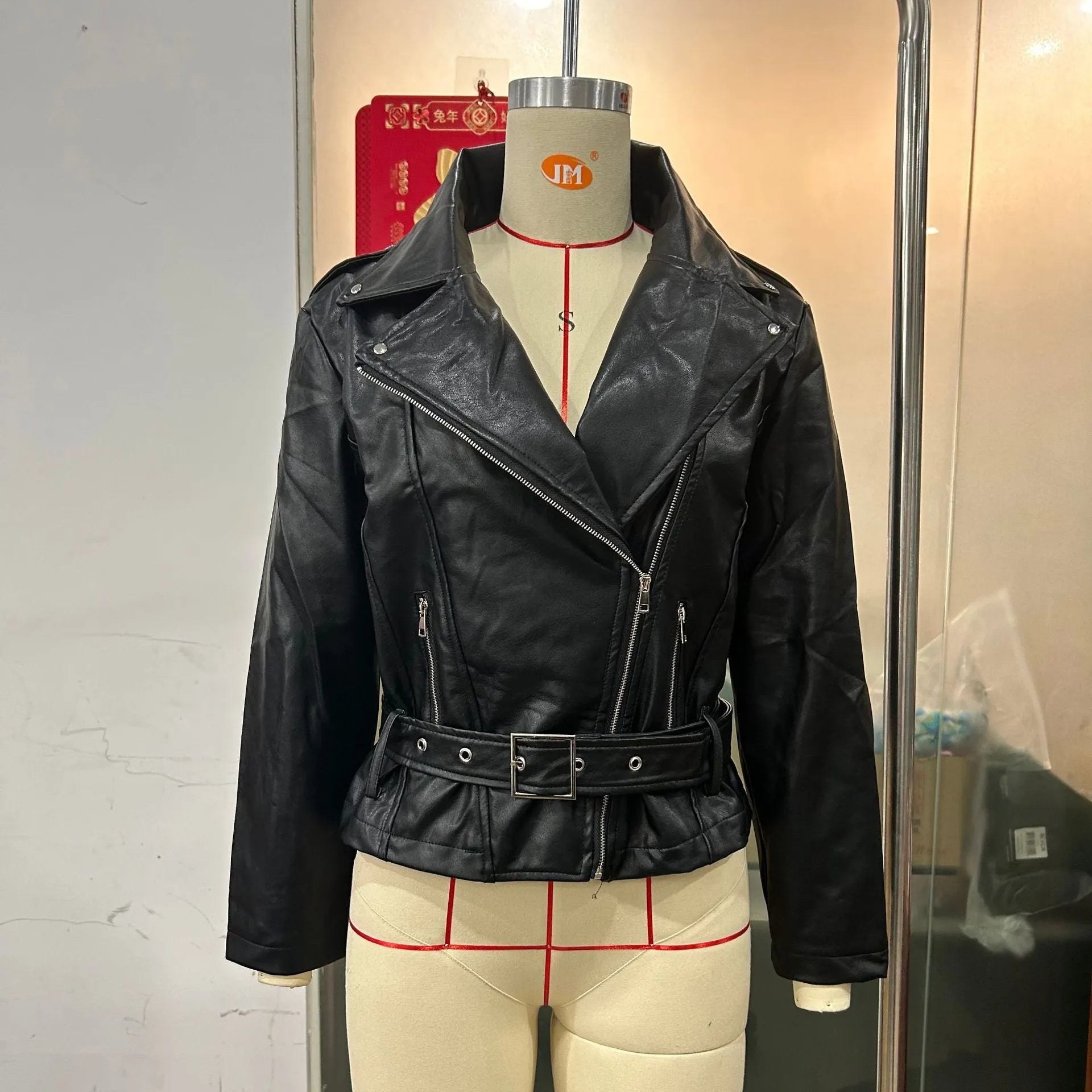 A black punk-style jacket with a lapel, short belt, and Peter Pan collar on a hanger.
