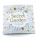 Adult DIY colouring book Secret Garden model open to a detailed black and white cartoon illustration page.