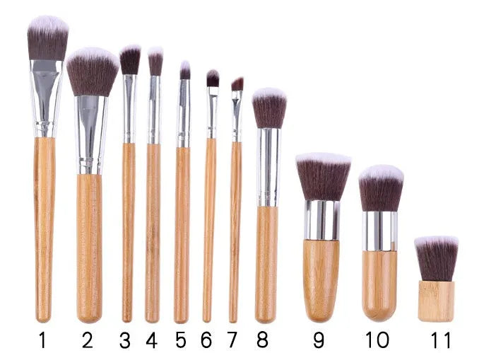 11 bamboo handle makeup brushes arranged on linen bag, including foundation blush and eye shadow brushes
