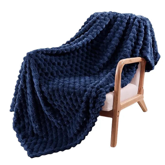 Soft camel-coloured plaid fleece blanket for children folded on a bed.