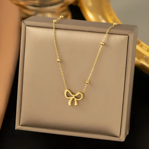Gold bow necklace with titanium steel cross chain on white background