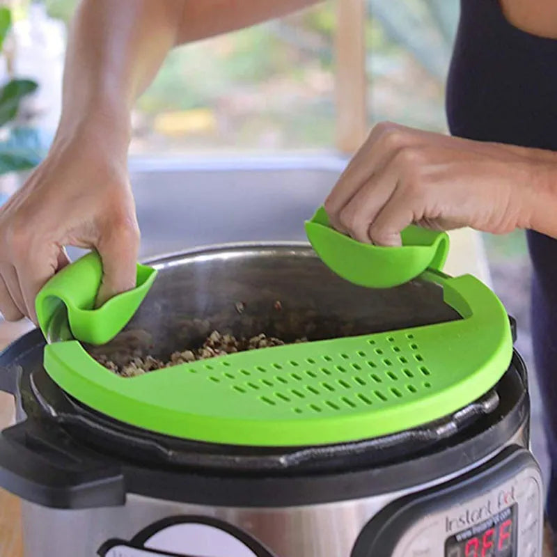 Black silicone food oil drainer snapped onto a pot rim, with liquid being poured off