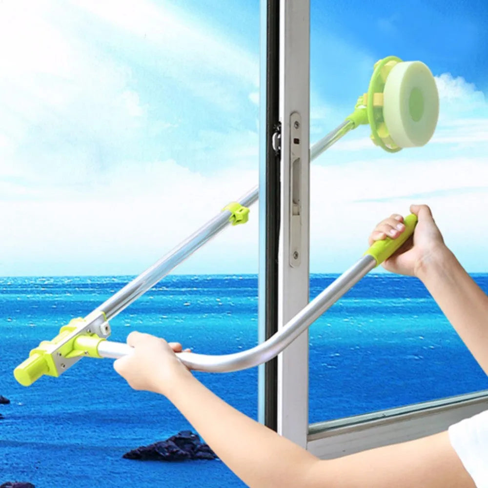 Green telescopic glass wiper with extendable handle resting on a windowsill