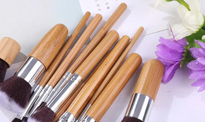 11 bamboo handle makeup brushes arranged on linen bag, including foundation blush and eye shadow brushes