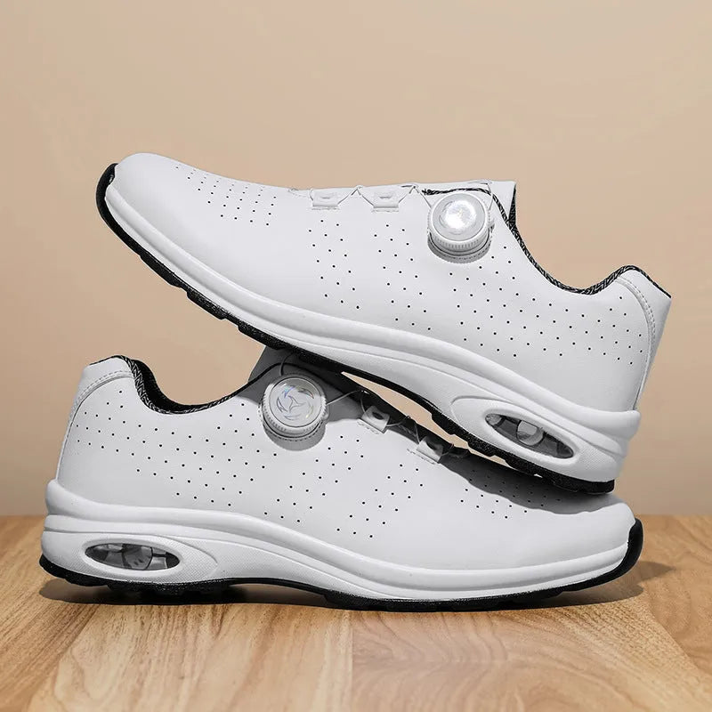 Low-top black and white tennis shoes with mesh uppers, cross shoulder straps, and a flat composite sole.