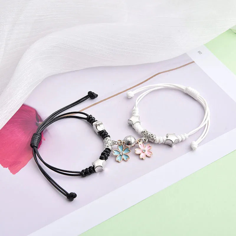Pair of magnetic suction bracelets with alloy charms in various love and friendship themed designs on a wrist.