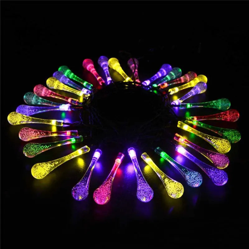 Solar-powered LED outdoor string lights with water drop-shaped pendants in garden setting