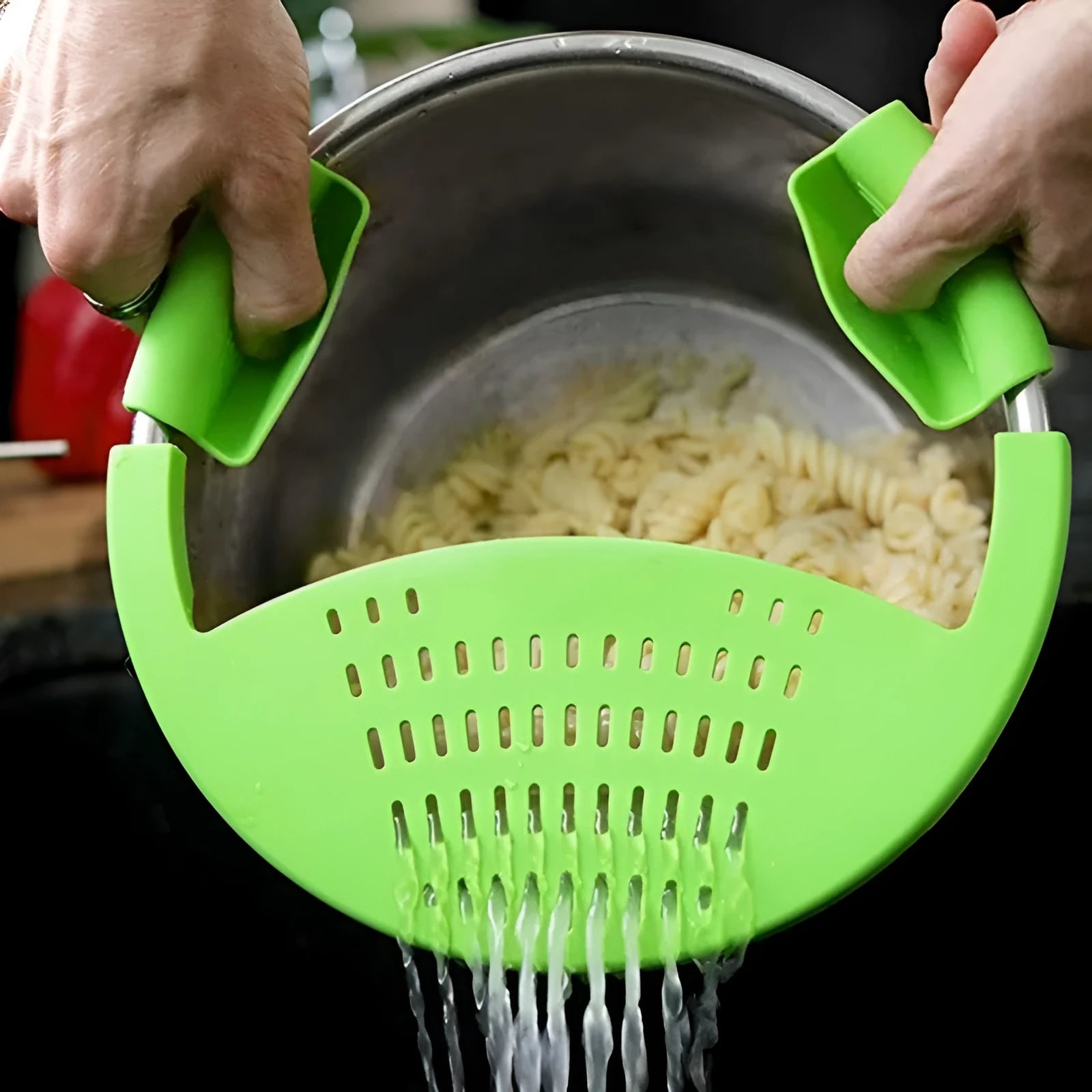 Black silicone food oil drainer snapped onto a pot rim, with liquid being poured off
