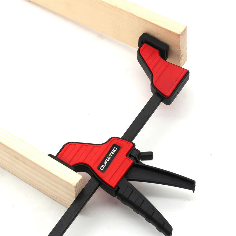 Black plastic woodworking clamp with quick-release lever and soft rubber grip pads