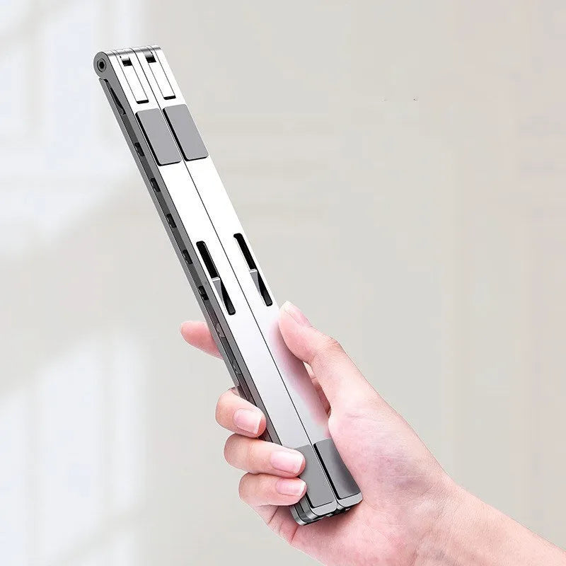 Folding flat aluminium alloy laptop stand in grey, 255x35x13mm, angled to show silicone pads and hinge mechanism