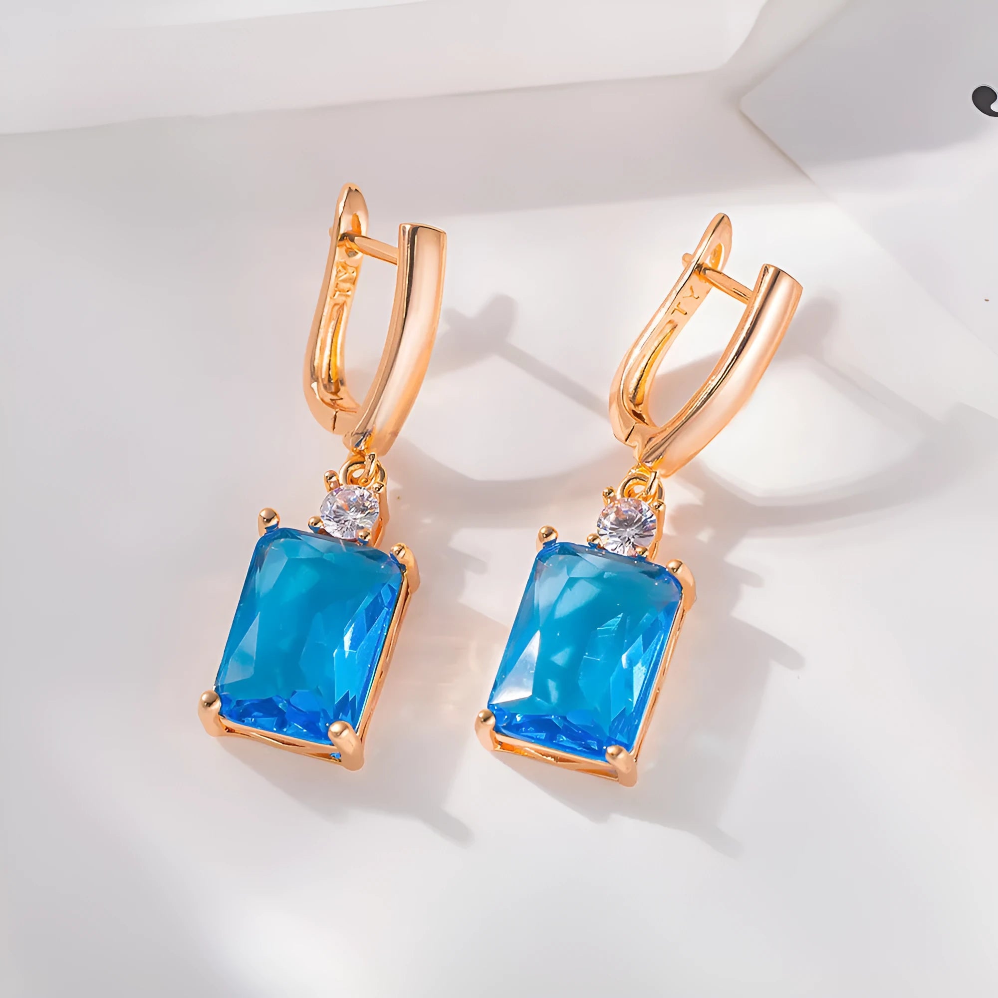 A pair of square-shaped gold-coloured electroplated earrings on a flat surface.