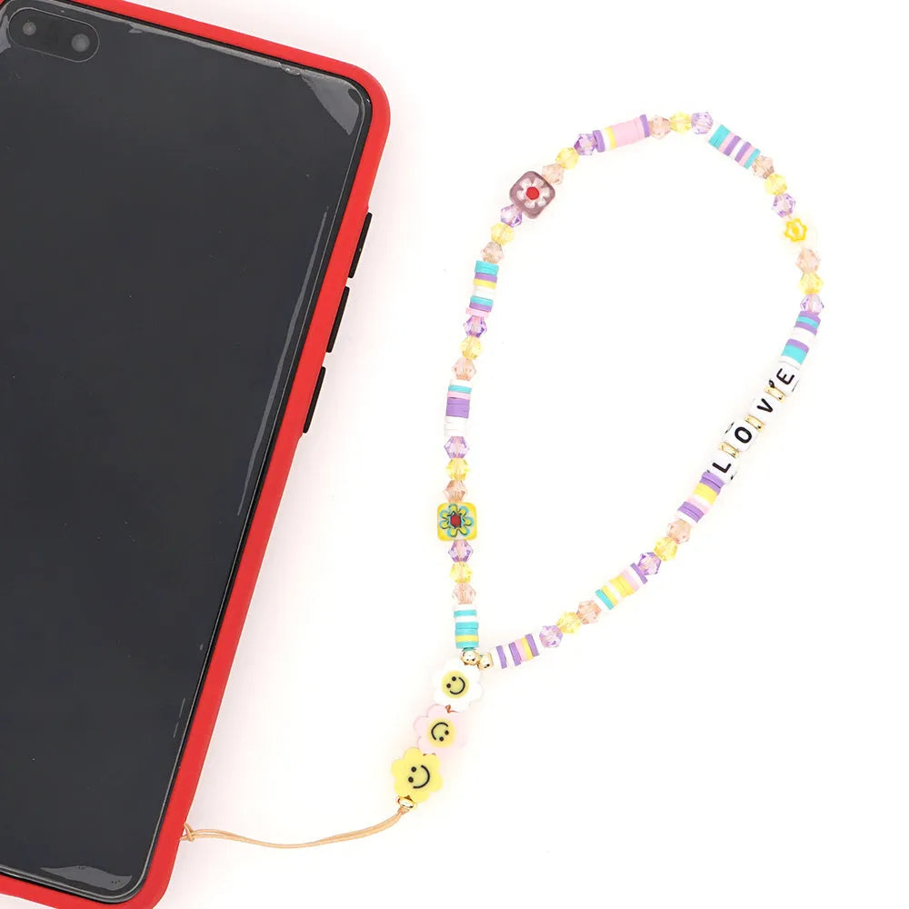 Handmade bohemian smiley soft ceramic beaded phone chain with crystal and acrylic letter beads on a light background