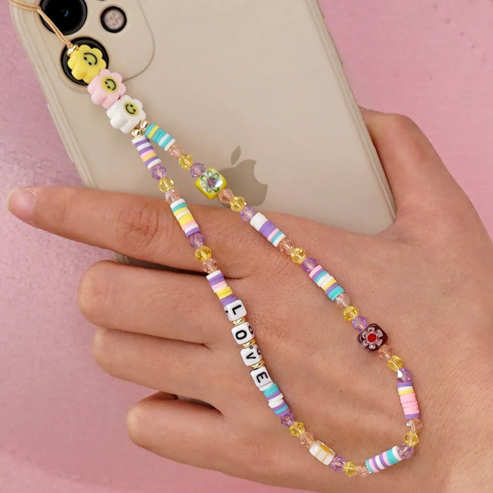 Handmade bohemian smiley soft ceramic beaded phone chain with crystal and acrylic letter beads on a light background