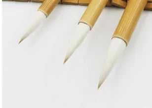 Three traditional Chinese calligraphy brushes with bamboo handles and woolen hair tips, shown in large, medium, and small sizes.