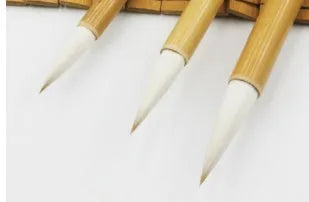 Three traditional Chinese calligraphy brushes with bamboo handles and woolen hair tips, shown in large, medium, and small sizes.