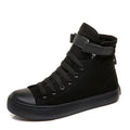 Pair of women's high-top canvas shoes with Velcro strap, black colour, rubber sole on a light background