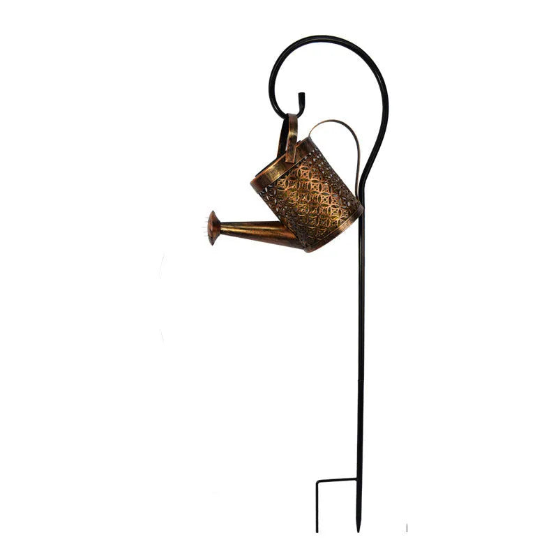 Enchanted watering can solar lamp with warm white star-shaped LED lights in a garden setting