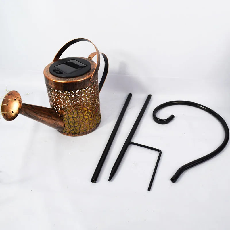 Enchanted watering can solar lamp with warm white star-shaped LED lights in a garden setting