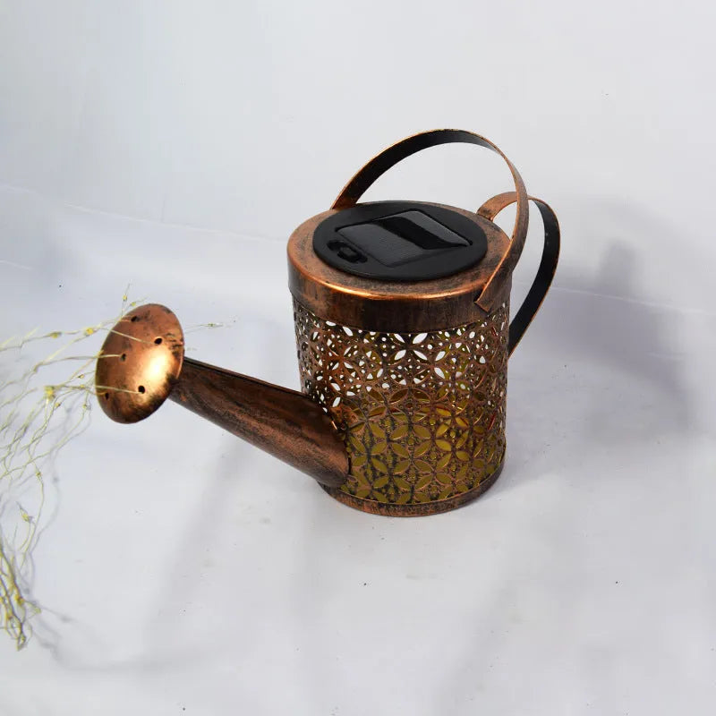 Enchanted watering can solar lamp with warm white star-shaped LED lights in a garden setting