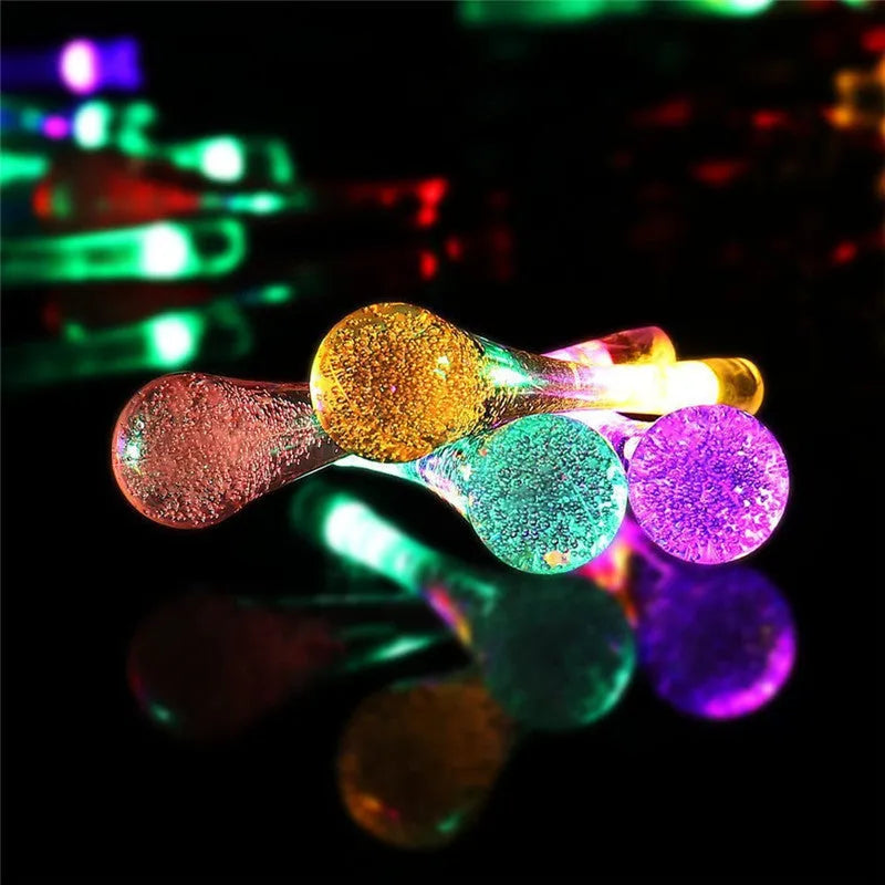 Solar-powered LED outdoor string lights with water drop-shaped pendants in garden setting