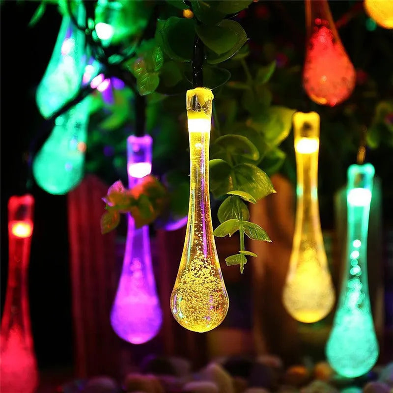 Solar-powered LED outdoor string lights with water drop-shaped pendants in garden setting