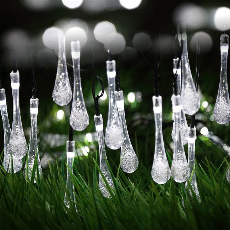 Solar-powered LED outdoor string lights with water drop-shaped pendants in garden setting