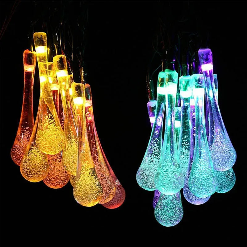 Solar-powered LED outdoor string lights with water drop-shaped pendants in garden setting