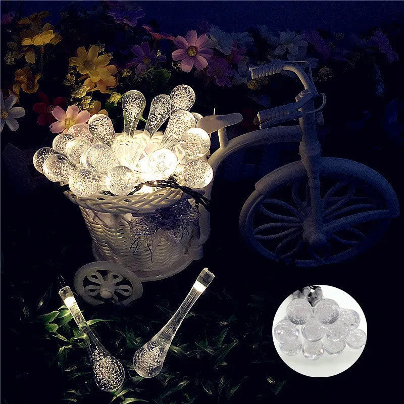 Solar-powered LED outdoor string lights with water drop-shaped pendants in garden setting