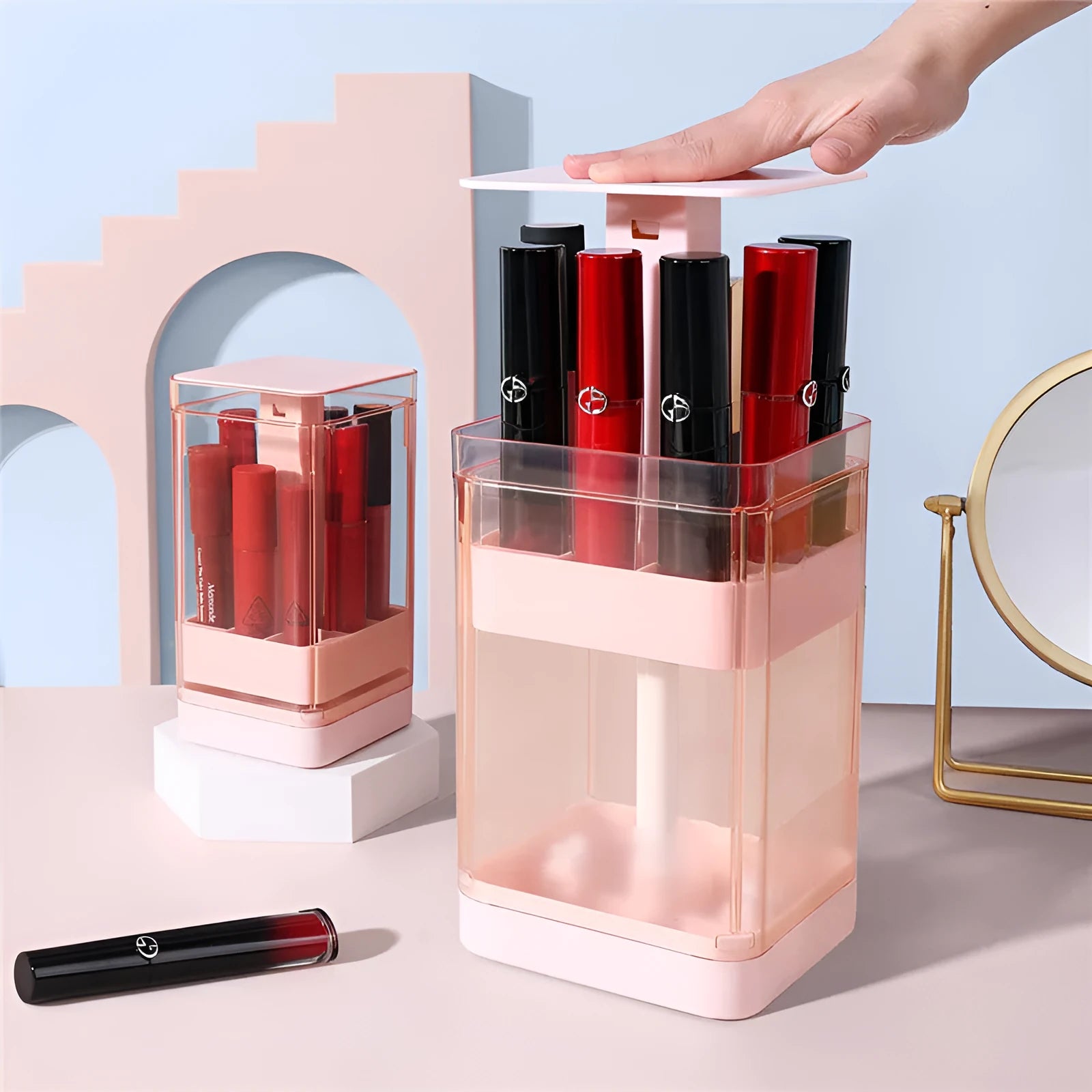 Press lift lipstick storage box with dust cover in pink colour on a desktop