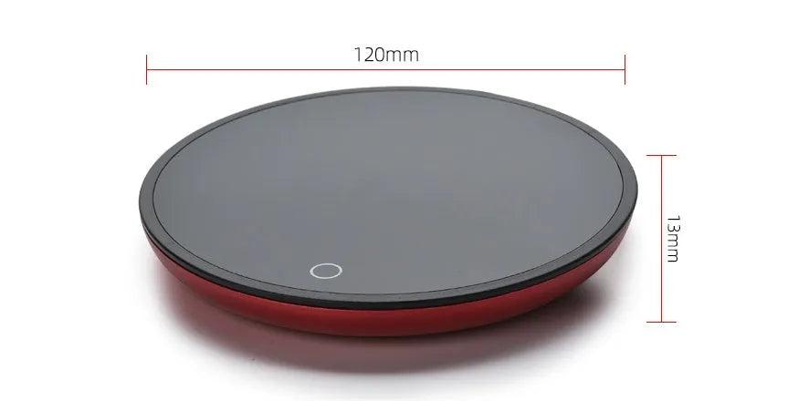Black circular coffee mug warmer with a tempered glass surface on a desk.