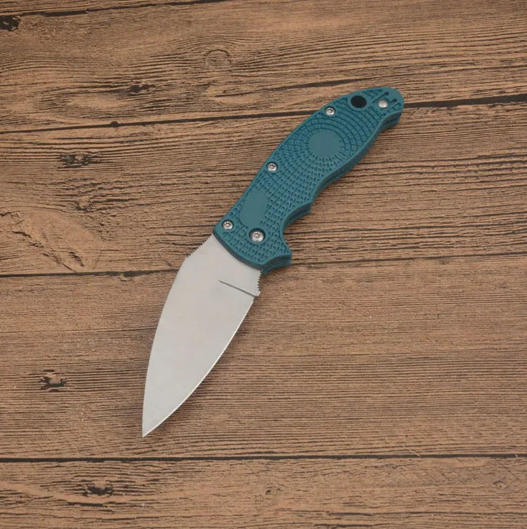 Portable folding fruit knife with black handle and silver 9CR13MOV blade on a wooden surface