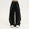 Black pleated wide-leg hip hop sports trousers on a hanger, showing loose fit and striped pattern.