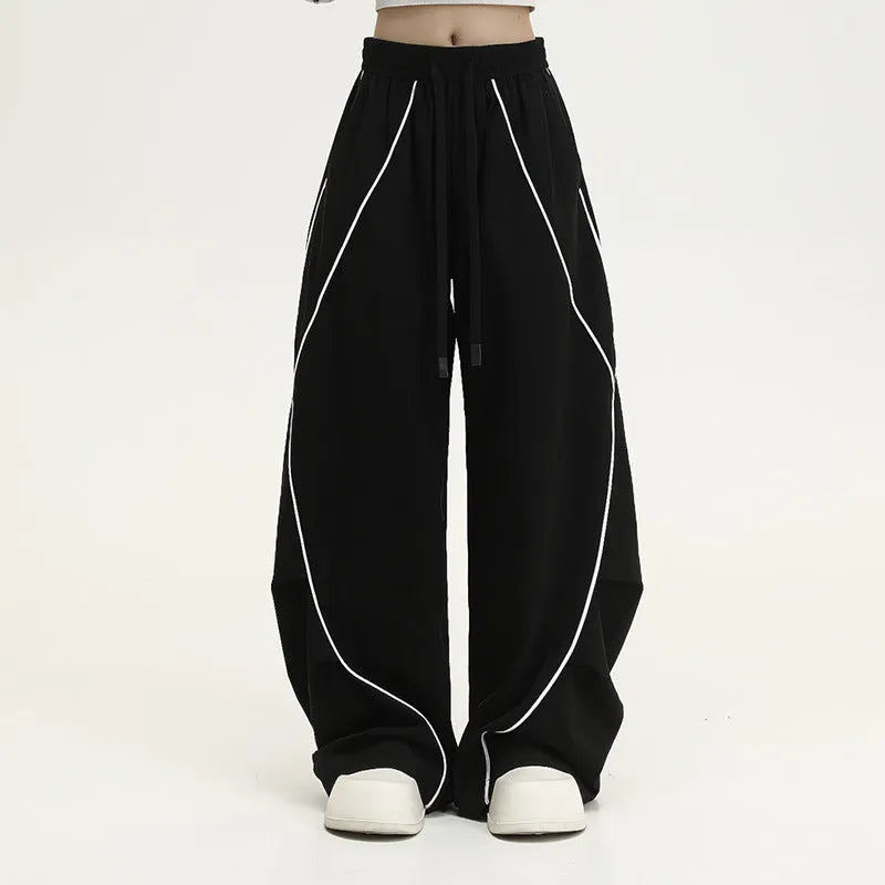 Black pleated wide-leg hip hop sports trousers on a hanger, showing loose fit and striped pattern.