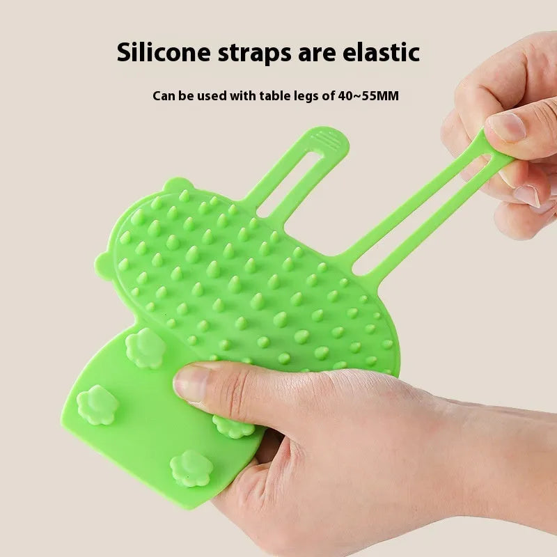 Silicone pet massage comb with adjustable strap attached to table leg