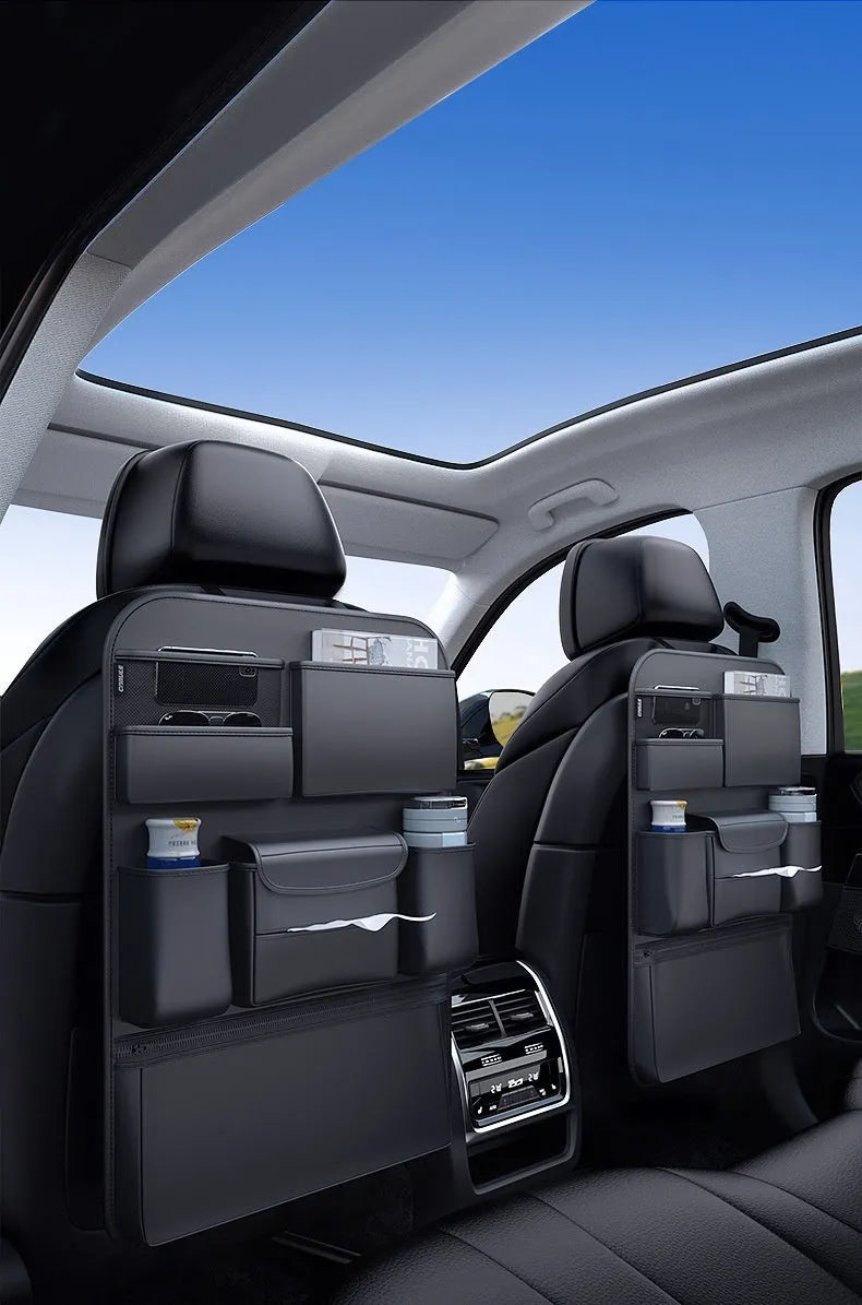 Black leather car seat back hanging storage organiser bag with handle shown mounted on a headrest.