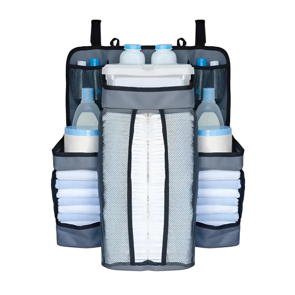 Gray baby diaper organizer hanging on a crib rail with compartments for nappies and wipes