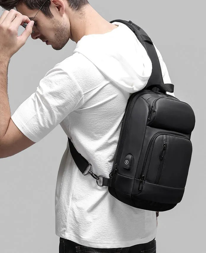 Black PVC outdoor shoulder bag showing medium size, shoulder strap, and internal pocket organisation