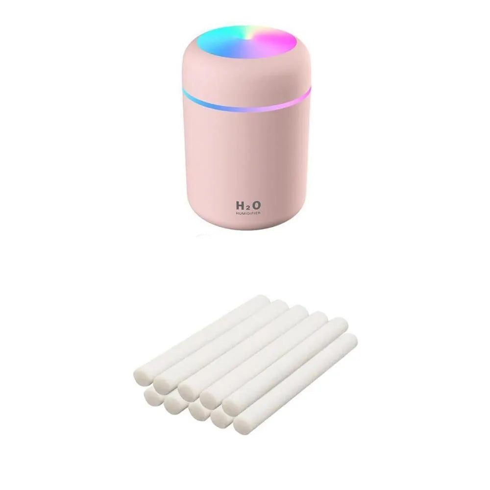Pink USB desktop humidifier with LED lights and water tank on a wooden desk.