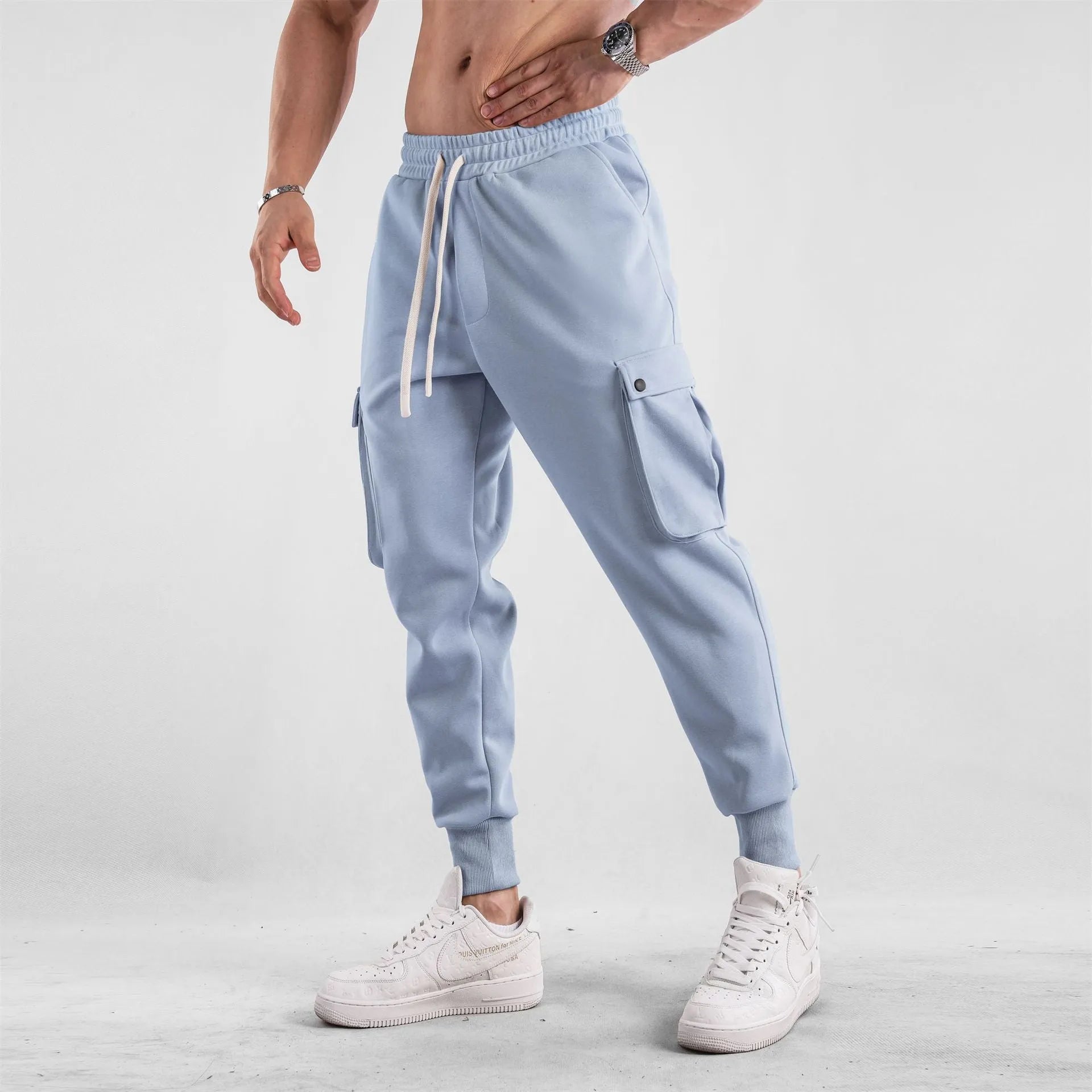 Men's loose-fit light grey cotton sports trousers with ankle tie and side pockets.