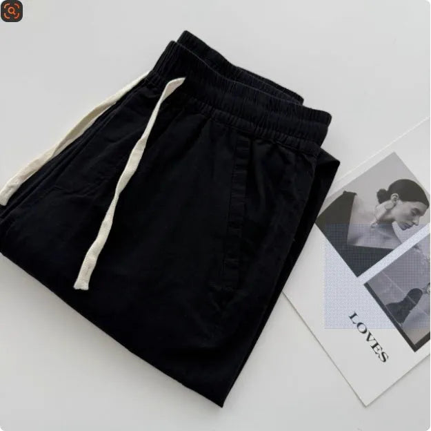 Man wearing beige loose straight leg casual trousers with a drawstring waistband.