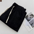 Man wearing beige loose straight leg casual trousers with a drawstring waistband.