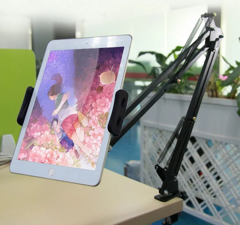 Black adjustable phone and tablet stand holding a mobile device on a desk.