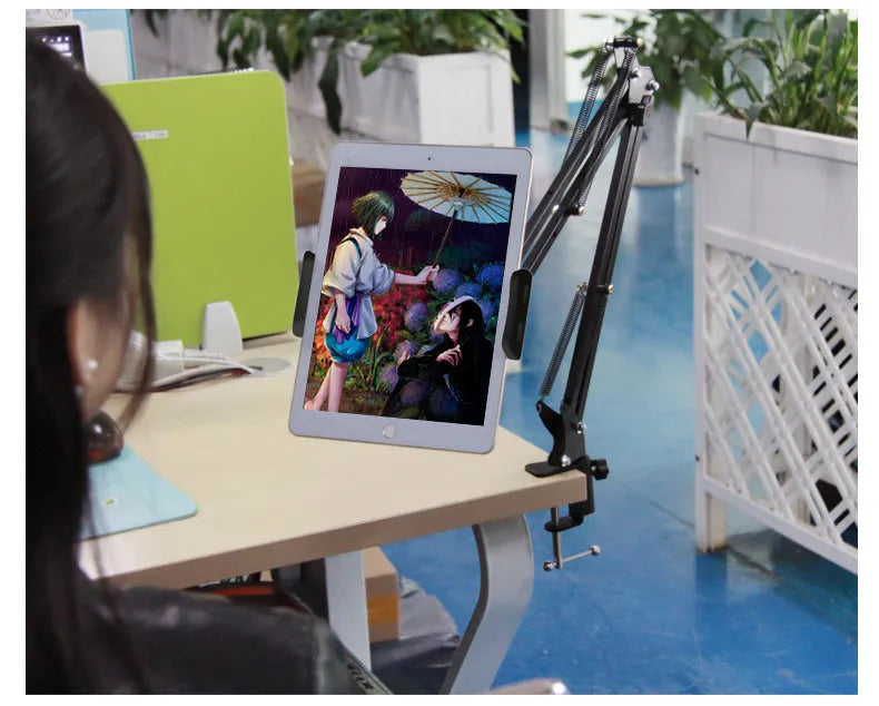 Black adjustable phone and tablet stand holding a mobile device on a desk.