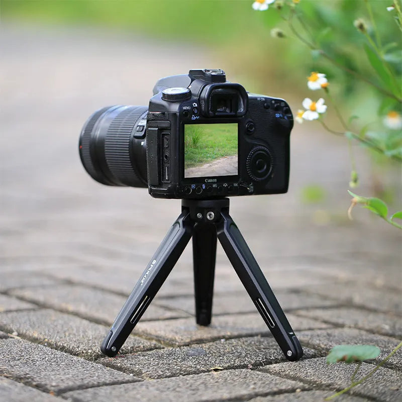 Metal mini tripod with non-slip rubber feet, 15cm max height, black, on uneven outdoor surface