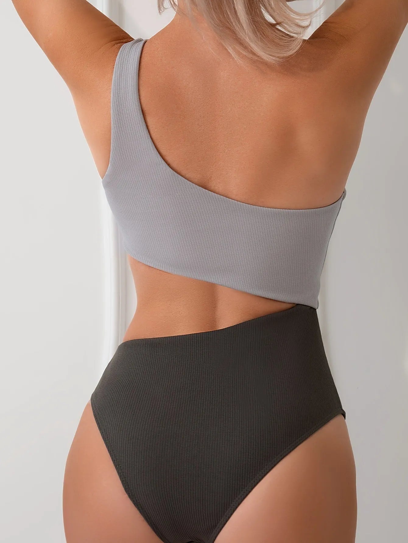 Light grey one-shoulder one-piece swimsuit on a mannequin, solid colour polyester fabric.