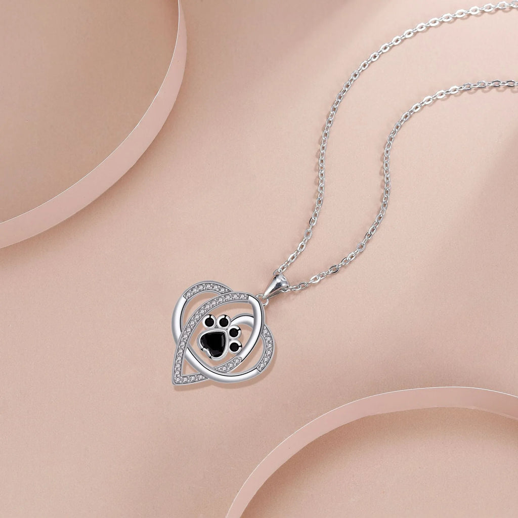 Close-up of a women's copper necklace with a dog paw print pendant on a cross chain.