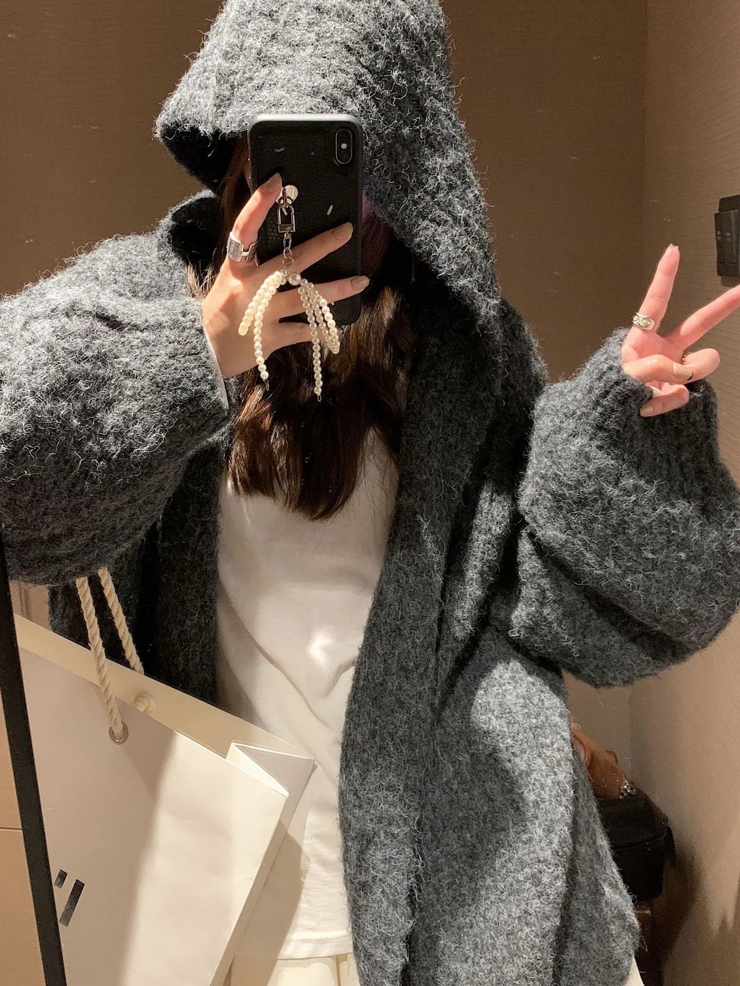Woman wearing a loose-fit, chunky knit hooded cardigan in a macaron colour.