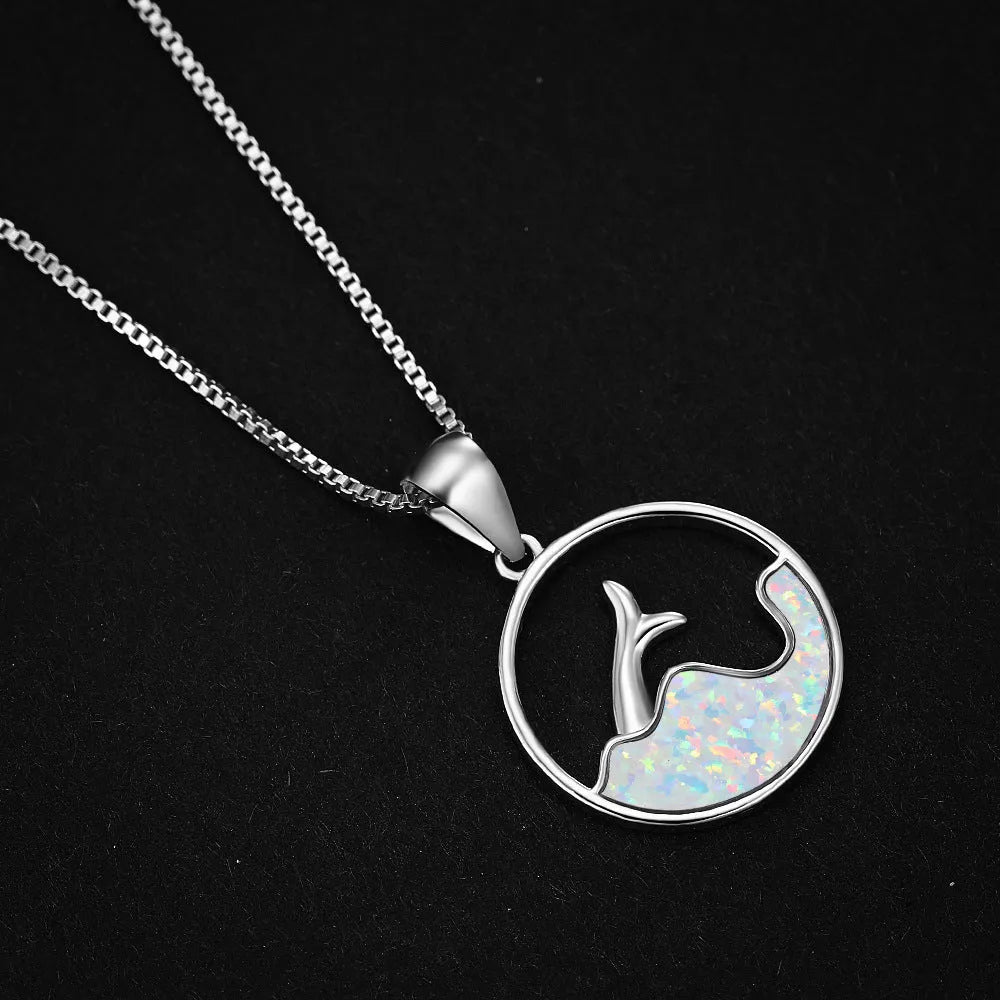 Close-up of a white gold plated sea fishtail pendant necklace with a round blue opal stone.