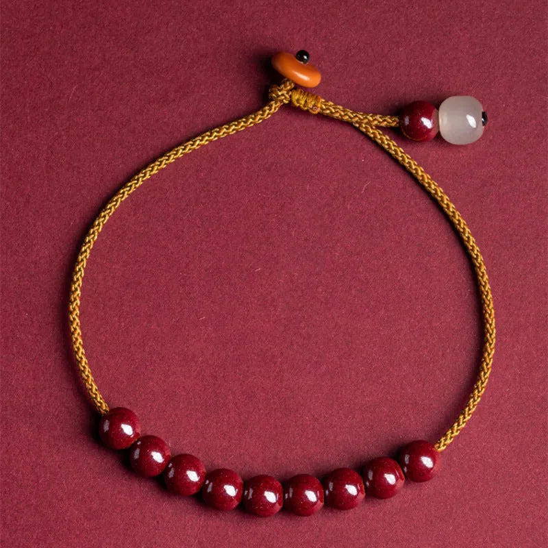 Hand-woven geometric bracelet made from raw Cinnabar and Hetian Jade ore on a wrist.