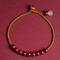 Hand-woven geometric bracelet made from raw Cinnabar and Hetian Jade ore on a wrist.